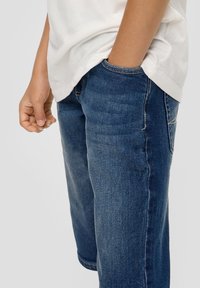 Shorts en denim bleu foncé, avec un design classique à cinq poches et de subtils détails de décoloration. Texture lisse avec un léger effet de délavage.