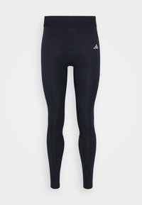 Schwarze sportliche Leggings mit enger Passform, aus dehnbarem Stoff. Mit einem breiten, elastischen Bund und einem kleinen weißen Logo an der Seite.