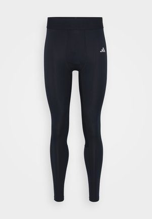 Schwarze sportliche Leggings mit enger Passform, aus dehnbarem Stoff. Mit einem breiten, elastischen Bund und einem kleinen weißen Logo an der Seite.