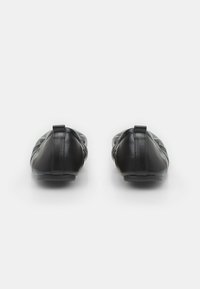 Bailarinas de cuero negro con textura suave, punteras redondeadas y diseño minimalista. La parte trasera tiene una pequeña lengüeta para facilitar su uso.
