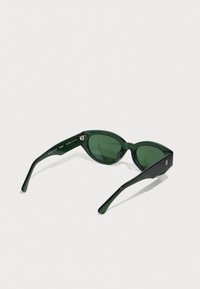 Green plastic sunglasses with a cat-eye shape, solid green lenses, and contrasting black temples featuring a small logo detail.