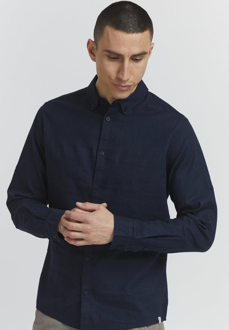 Chemise bleu marine à boutonnage, en tissu texturé, avec un col et des manches longues, des boutons aux poignets et un petit logo à l'ourlet.