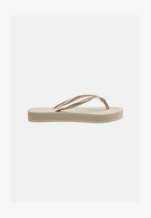 Infradito beige con plantare testurizzato e cinturini a forma di Y color bronzo lucido, mostrato di profilo su uno sfondo chiaro neutro.