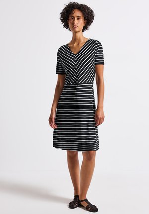 Robe à rayures noires et blanches avec décolleté en V, manches courtes et jupe évasée, présentant un motif en chevrons au niveau du buste et une texture de tissu douce.