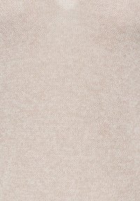 Primer plano de una tela de punto beige que muestra una textura tejida detallada y un patrón de puntadas uniforme.
