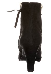 Bottine en suède noir avec un talon effilé, dotée d'une fermeture éclair à l'arrière et d'un détail de lacet décoratif en haut. Texture lisse, forme élégante.