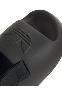 Svart slide-sandaler med en texturerad ovandel, en framträdande logotyp och ett justerbart rem. Designade med en rundad fotbädd och öppen tå.