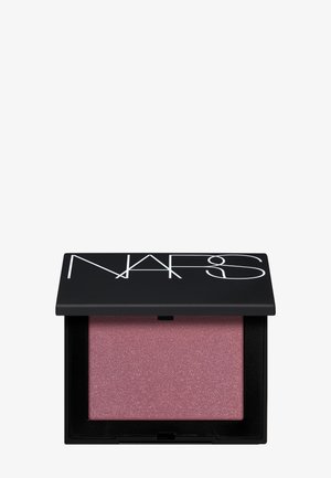 Petit boîtier noir de blush avec le logo NARS, ouvert pour révéler une poudre rose mauve irisée à l'intérieur.