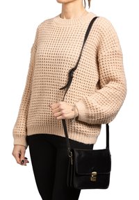 Maglione beige a maglia con un motivo testurizzato, abbinato a una borsa a tracolla in pelle nera con chiusura dorata e tracolla regolabile.