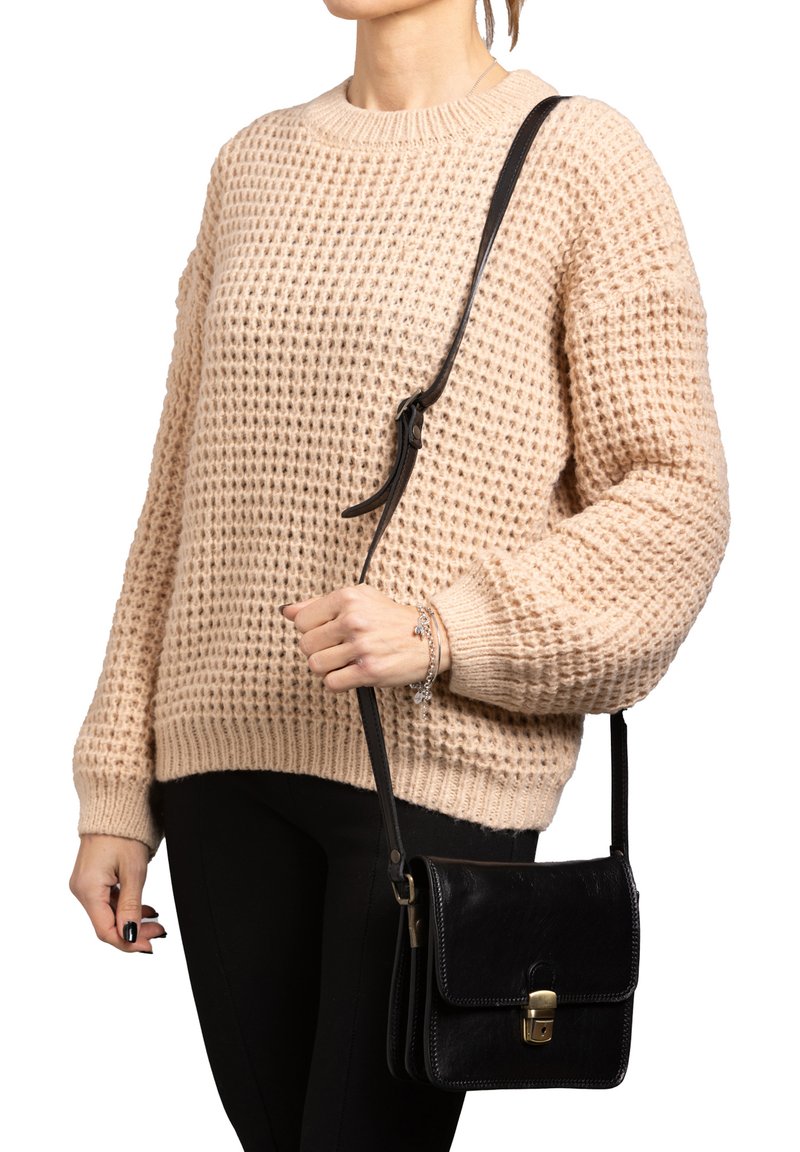 Maglione beige a maglia con un motivo testurizzato, abbinato a una borsa a tracolla in pelle nera con chiusura dorata e tracolla regolabile.