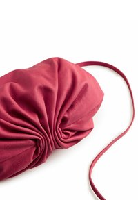 Pochette en tissu bordeaux texturé, avec un design froncé au centre et une fine bandoulière s'étendant d'un côté.