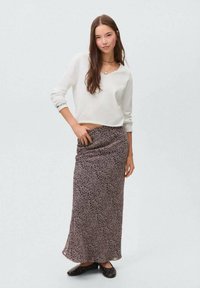 Lättviktig vit långärmad topp som är matchad med en lång, mönstrad mörk kjol med små blommönster. Svarta ballerina med nitar.