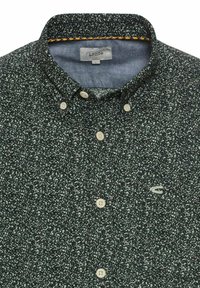 Button-up skjorte i mørkegrøn med et prikket mønster. Har krave i klassisk stil, beige knapper og en kontrastfarvet detalje ved indersiden af kraven.