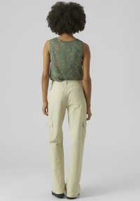 Groene bloemige top zonder mouwen van textuurstof, gecombineerd met lichtgele cargobroek met zijzakken en een ontspannen pasvorm.
