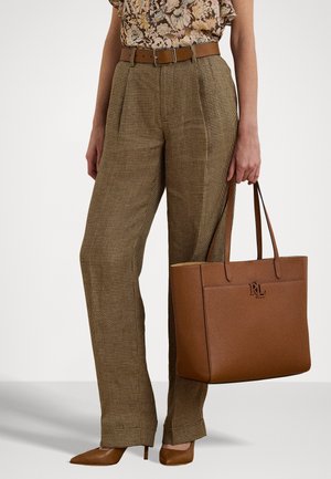 Saco tote de pele castanha com logótipo em relevo, combinado com calças de cintura alta em padrão bege xadrez e sapatos de salto agudo castanhos, blusa floral.