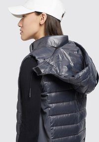 Marineblauer Puffer-Westen mit gestepptem Design, abnehmbarer Kapuze und schwarzen gerippten Ärmeln. Bietet ein schlankes Design mit glänzender Oberfläche.