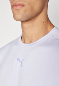 Svetlofialové športové tričko, s okrúhlym výstrihom, krátkymi rukávmi, s jemným fialovým logom Puma na prednej strane. Hladká látka s jemným leskom.