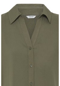 Chemise boutonnée vert olive avec col pointu et étiquette de marque visible à l'intérieur de l'encolure.