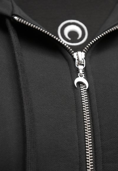 Camisola preta com fecho de correr prateado, tecido texturizado e um logótipo circular na área do peito. Ajuste suave e confortável.