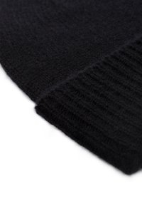 Gorro de punto negro con un acabado texturizado, que presenta un puño acanalado y un material blando y difuso. La forma es redondeada en la parte superior.