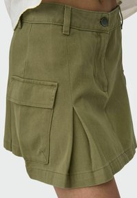 Pantaloni cargo verde oliva realizzati in tessuto resistente, con tasca laterale, design plissettato e chiusura a bottone classica.