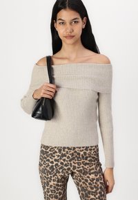 Beige ribbed knit off-shoulder sweater paired with leopard print pants. Black handbag features a zip closure and curved base.