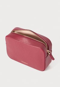 Pouch cosmetico in pelle rossa con finitura testurizzata, zip dorata e logo impresso. Forma rettangolare, design compatto per una facile conservazione.