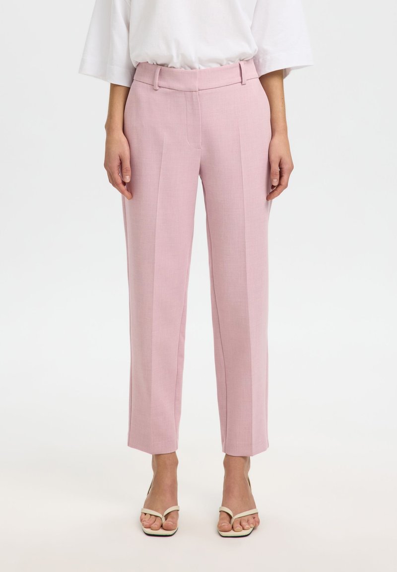 Ροζ παντελόνια με καλοραμμένη εφαρμογή και απαλό ύφασμα, με ψηλή μέση, δύο μπροστινές τσέπες και ίσια μπατζάκια, συνδυασμένα με πέδιλα με λουράκια.