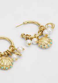 Orecchini a cerchio in oro con charm a forma di conchiglia, accenti di perle e dettagli turchesi, con anelli metallici intrecciati per un tocco di texture in più.