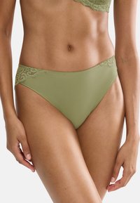 Olivengrønne bikinibukser med blonder langs livet, med glatt stoff, siddekning og sømløst design.