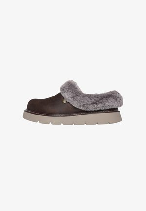 Zapatilla marrón con ribete de piel sintética gris y una suela gruesa beige. Punta redondeada, detalles cosidos y un pequeño logo en el lateral.