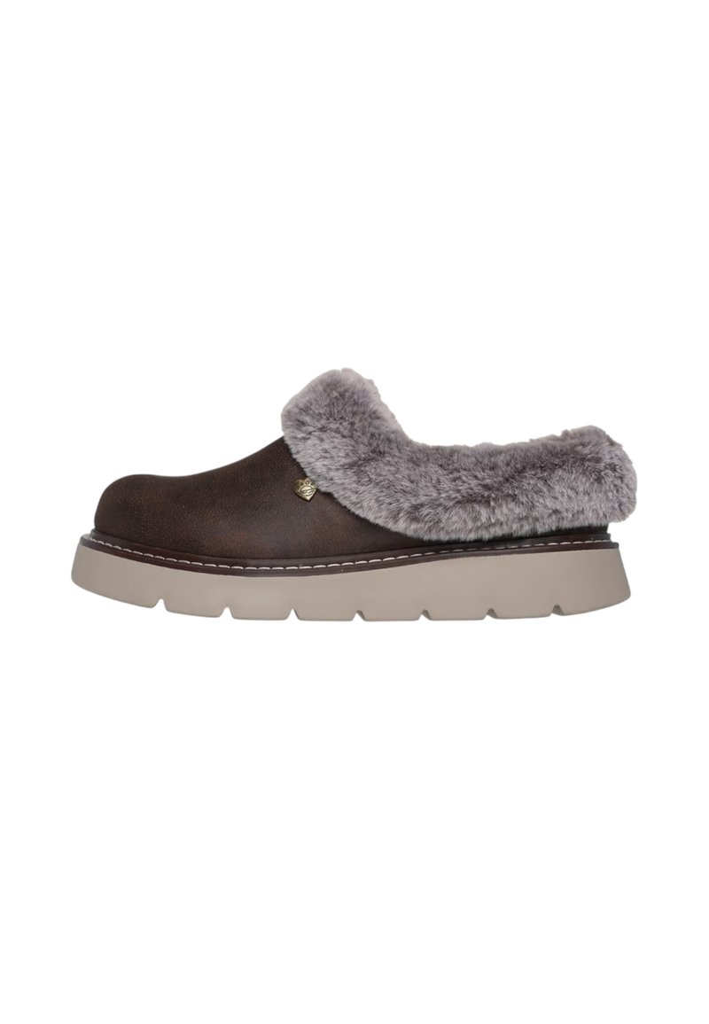 Zapatilla marrón con ribete de piel sintética gris y una suela gruesa beige. Punta redondeada, detalles cosidos y un pequeño logo en el lateral.