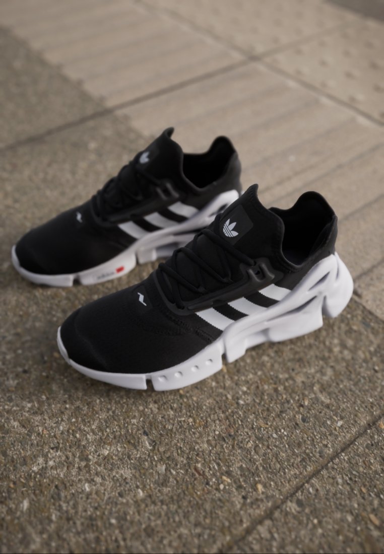 Svarta löparskor med vita detaljer, med en ventilerande nätövre, tre ränder-design och en tjock gummisål.