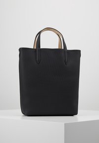 Sac cabas noir avec extérieur texturé, poignées robustes en cuir et intérieur uni. Forme carrée avec lignes épurées et accents minimalistes.