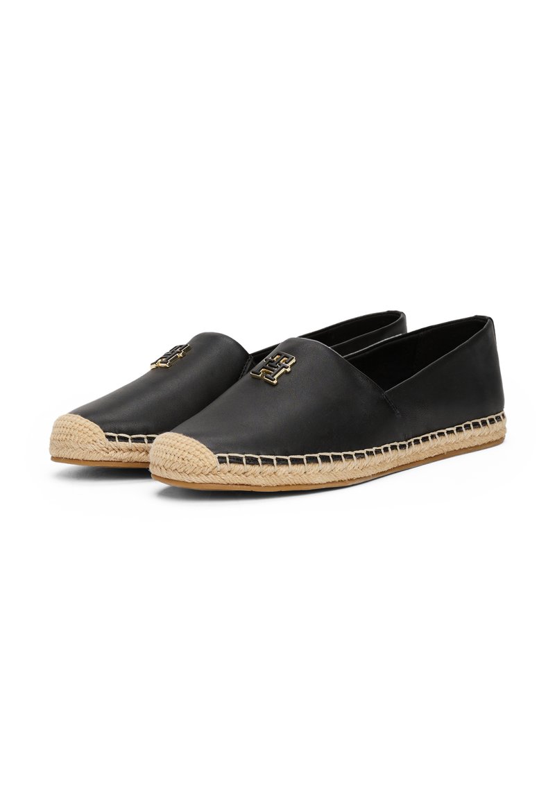 Espadrilles en cuir noir avec une semelle en jute, arborant un accent logo noir sur le dessus et un détail cousu le long du bord.