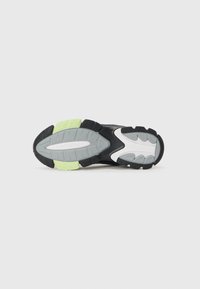 Black and gray athletic shoe sole with light green, white accents; textured rubber for grip, featuring a unique tread pattern.
