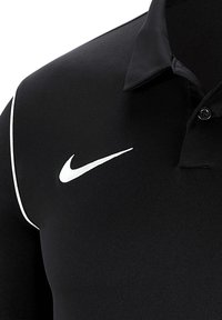 Černé polo tričko vyrobené z hladké tkaniny, které má bílé logo Nike na levé hrudi a bílé akcenty podél límce.