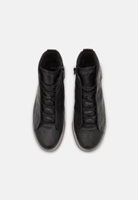Czarne wysokie trampki ze skóry z fakturowanym wykończeniem, z frontowym wiązaniem na sznurówki i bocznym zamkiem błyskawicznym. Gumowa podeszwa o płaskim profilu.