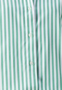 Kariertes Hemd mit vertikalen grünen und weißen Streifen, aus leichtem Stoff, mit glatter Textur und fünf weißen Knöpfen an der Vorderseite.