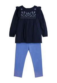 Mornarsko prugasta long-sleeve bluzica s cvjetnim vezom na prsima, u kombinaciji sa svijetloplavim tajicama od mekog, rastezljivog materijala.