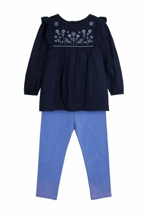 Mornarsko prugasta long-sleeve bluzica s cvjetnim vezom na prsima, u kombinaciji sa svijetloplavim tajicama od mekog, rastezljivog materijala.