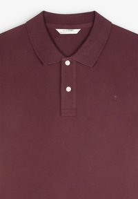 Bordeauxrode poloshirt met een gestructureerde stof, een klassieke kraag en twee witte knopen. Voorzien van een klein geborduurd logo vlakbij de borst.
