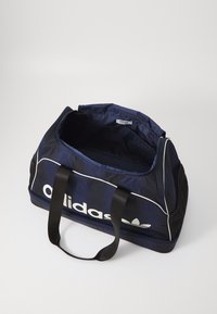 Marine duffelbagen laget av nylon med hvite striper og logo, med solide svarte håndtak og et romslig interiør uten lukking.