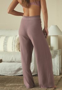 Plati kojinės, raštuoto trikotažo kelnės muted mauve spalvos, su aukštu liemeniu ir prigludusiomis rankovėmis. Medžiaga švelni ir elastinga.