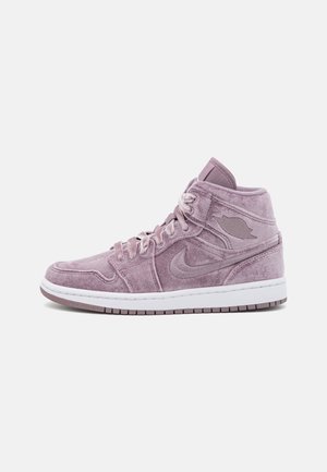 Sneaker alta in suede rosa con suola in gomma bianca, caratterizzata da un logo Nike cucito e lacci tonali. Texture liscia e collo imbottito.