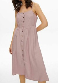 Blommig skjortklänning i ljusrosa tyg, med en åtsittande överdel, justerbara axelband och en flödande kjol med träknappar nedtill.