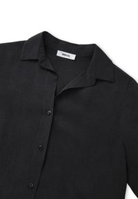 Black short-sleeve shirt made of lightweight fabric, featuring a pointed collar, front buttons, and a smooth texture. Label visible inside.
