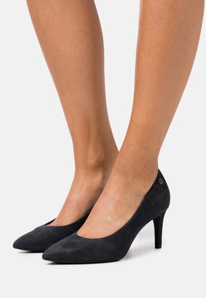 Escarpins noirs en daim à talons hauts avec un bout pointu et un décolleté avant bas. Présente un accent décoratif en logo argenté sur le talon.