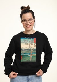 Felpa nera con un'opera d'arte stampata di alberi e un fiume in colori tenui. Il design include del testo in caratteri giapponesi.