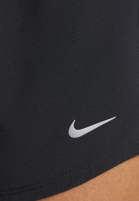Svarta sportshorts i mjukt, stretchigt material med en silverfärgad Nike-logotyp och prydliga sömmar längs fållen.